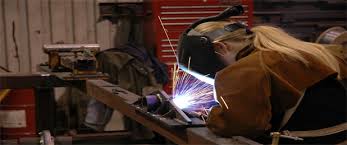 Female student welding with protective equipment on